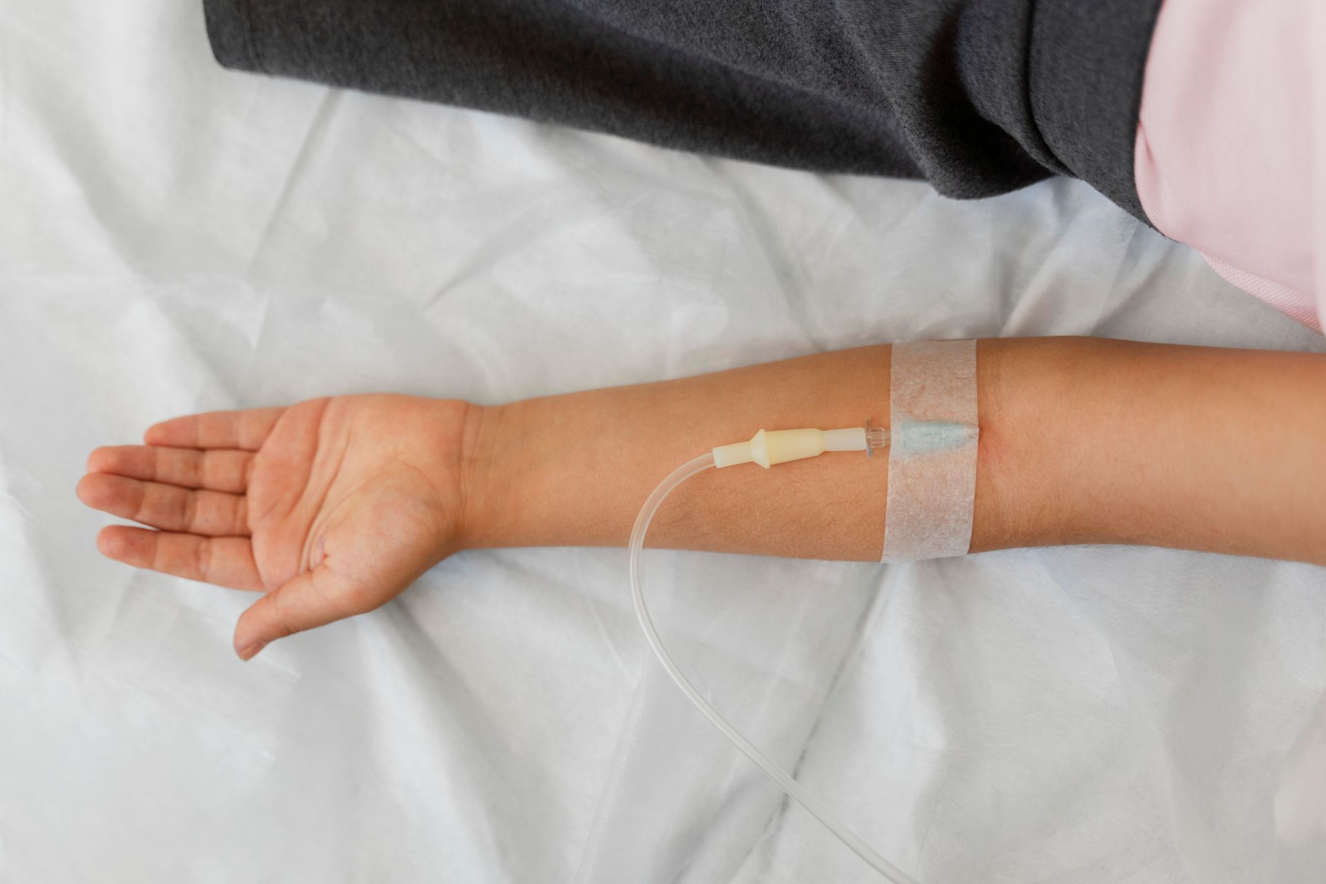 A person is laying on a bed with an iv in their arm.