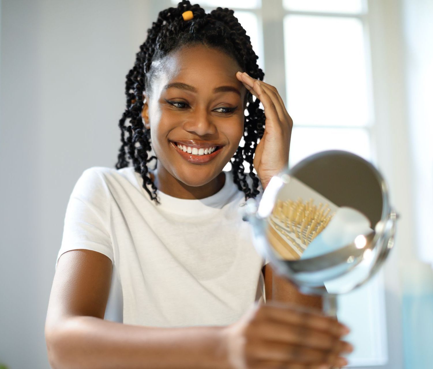 A woman is smiling while looking at herself in a mirror.