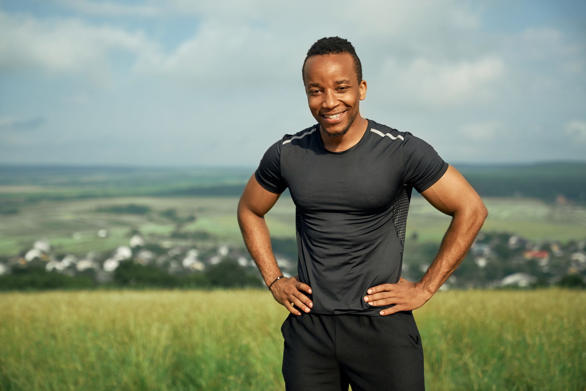 A man is standing in a field with his hands on his hips.