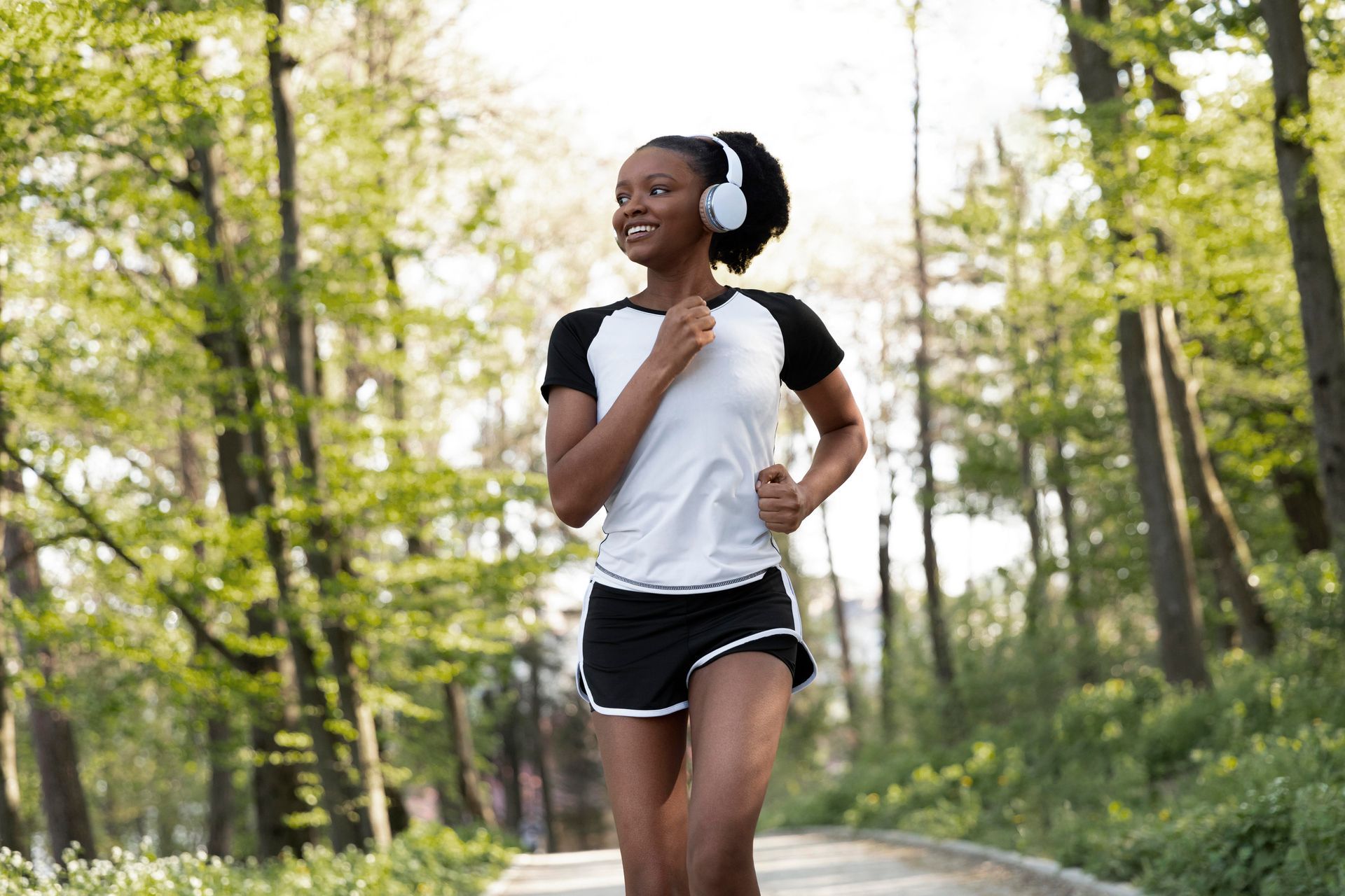 A woman wearing headphones is running in the woods.