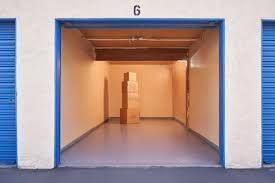 An empty storage unit with blue doors and boxes in it.