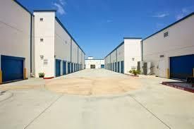 A row of warehouses with blue garage doors on a sunny day.