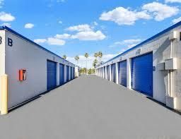 A row of storage units with blue doors on a sunny day.