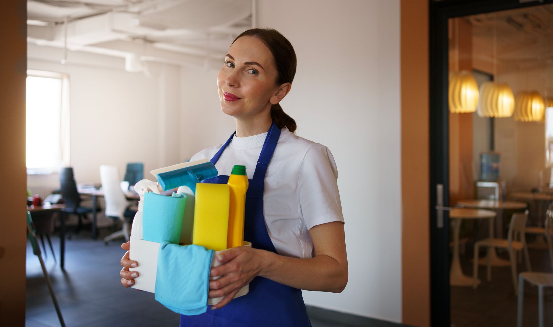 a woman is holding a stack of cleaning supplies in an office .