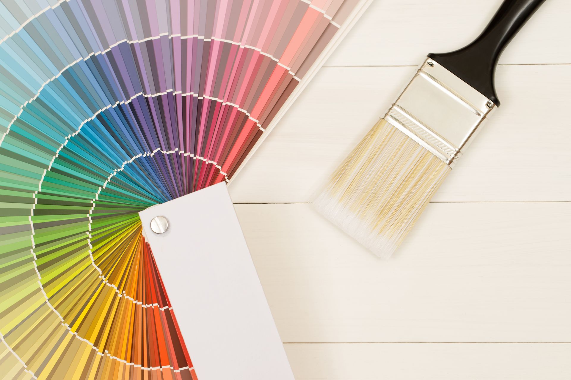 a paint brush is sitting next to a color palette on a white wooden table .