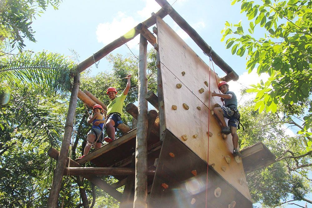 Duas pessoas estão escalando uma parede de escalada na floresta.