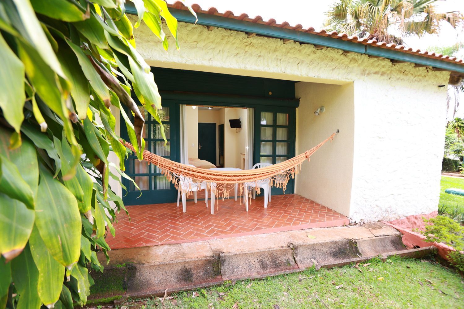 Um pátio com mesas e cadeiras sob um guarda-sol verde