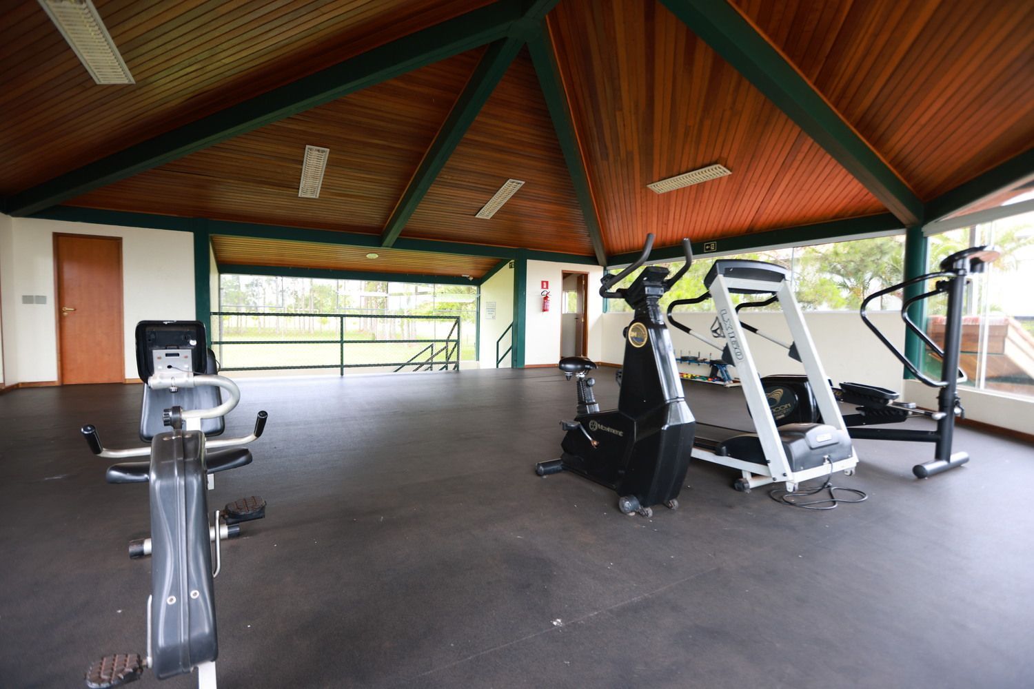 Três homens estão levantando pesos em frente a um espelho em uma academia.