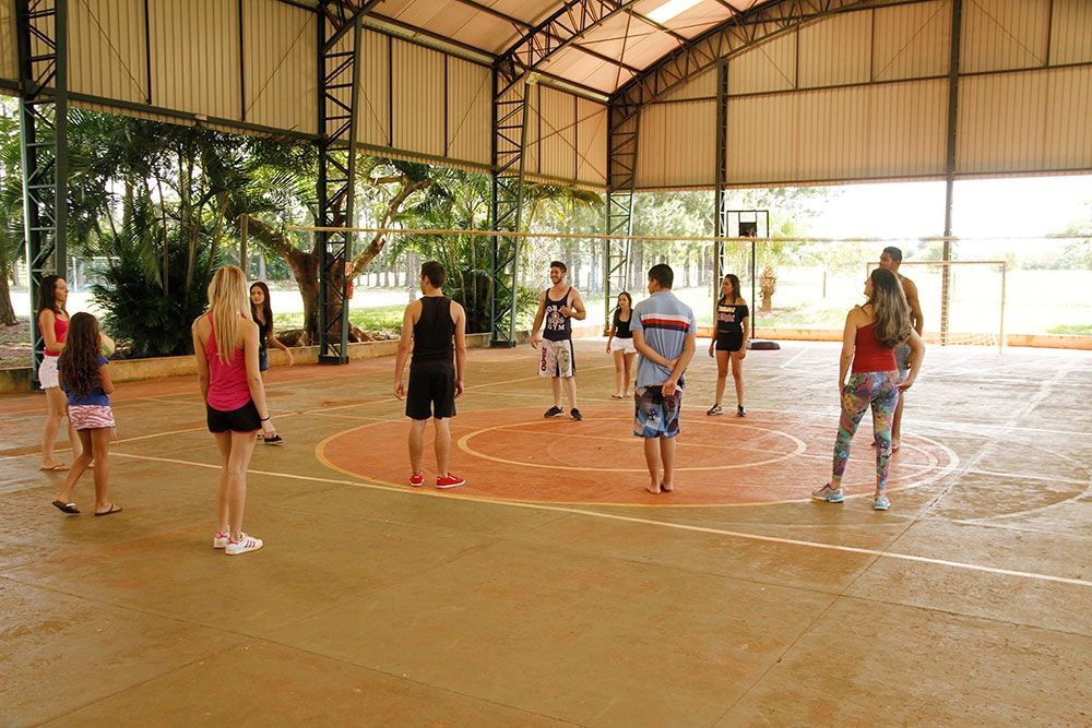 Um grupo de pessoas está em pé formando um círculo em uma quadra de basquete.