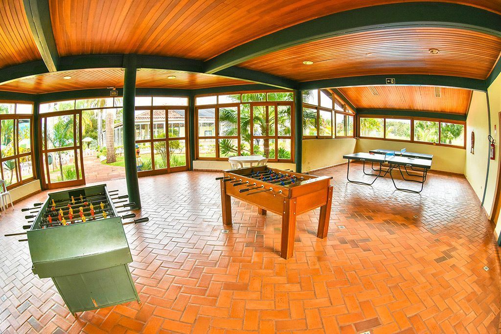 Uma sala grande com uma mesa de pebolim e mesas de pingue-pongue