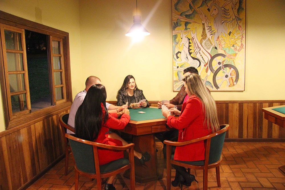 Um grupo de pessoas está sentado ao redor de uma mesa jogando cartas.