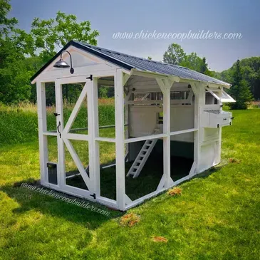 A white chicken coop is sitting on top of a lush green field.