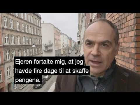 Mand taler på balkon i en by, teksten lyder 