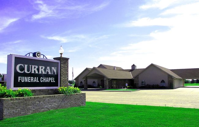 The front door of a house with a porch and plants in front of it.