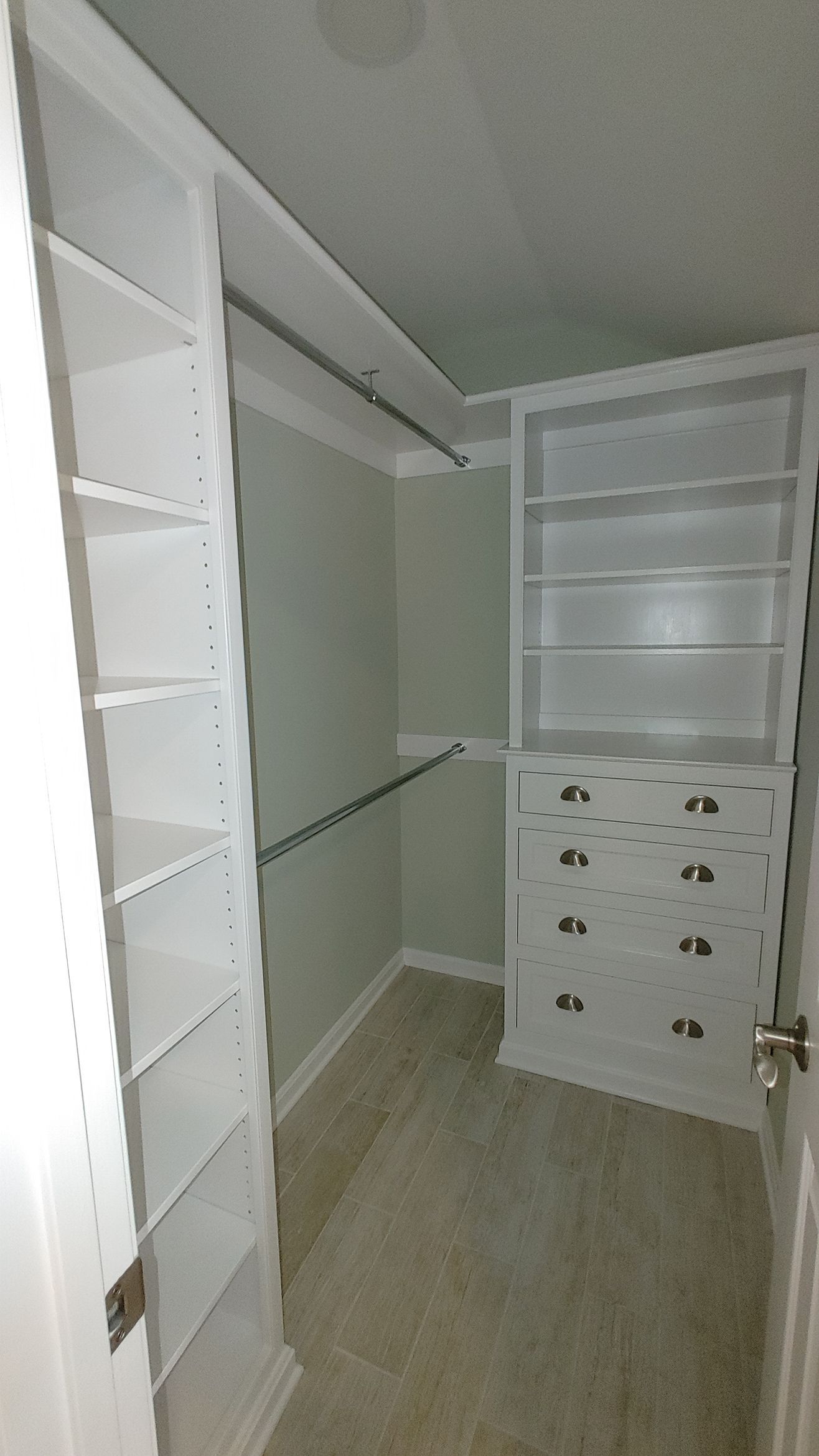 A modern kitchen featuring wood cabinets, white upper cupboards, a large island with three stools, and wooden floors.