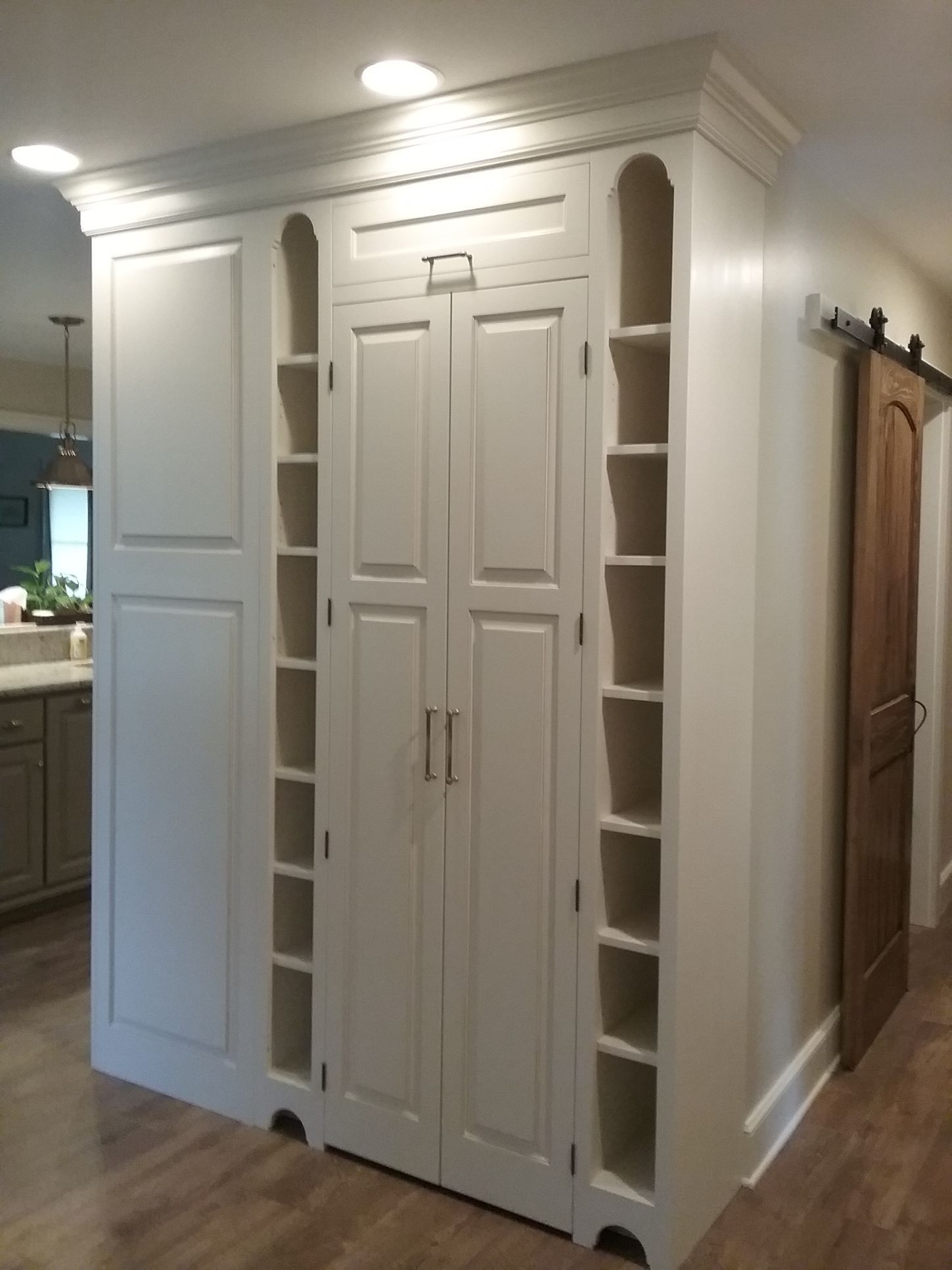 A modern kitchen with white cabinets, wood-tone upper cabinets, black countertops, and a dark stone backsplash.