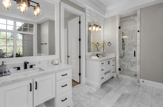 Modern bathroom with a marble vanity, white sink, wall-mounted toilet, and wood-toned horizontal wall tiles.