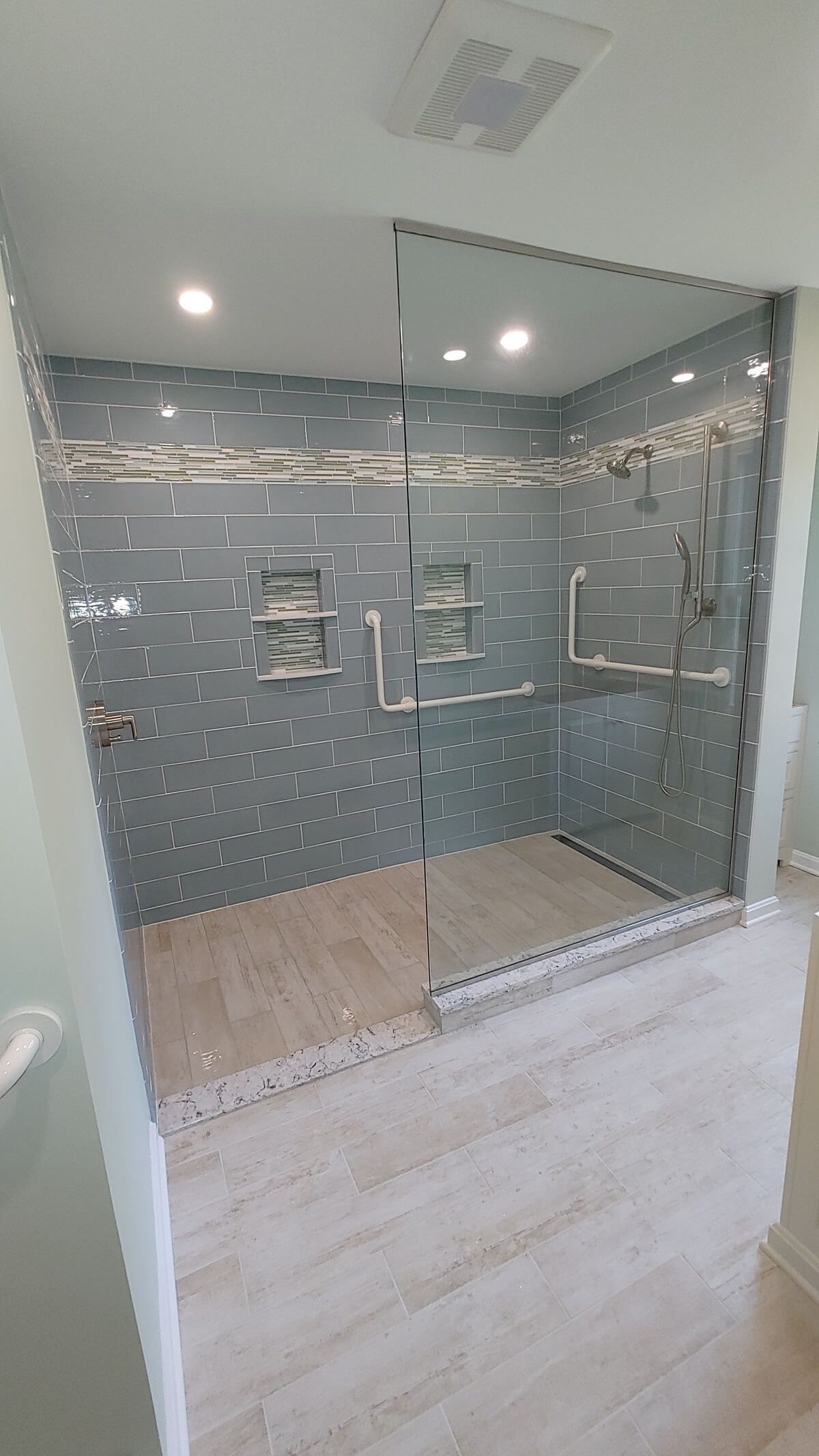A bright, modern bathroom featuring a white soaking tub, gold fixtures, a glass-enclosed shower, and navy blue cabinetry.