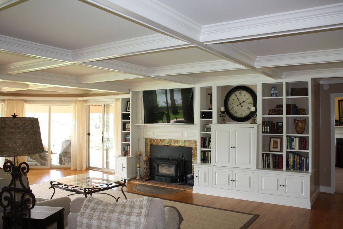 A professional in workwear uses a spirit level and screwdriver to install a drawer in a modern kitchen cabinet.