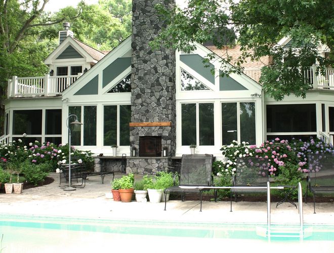 A two-story suburban home with tan siding, a front-facing garage, stone accents, and a covered entry porch.