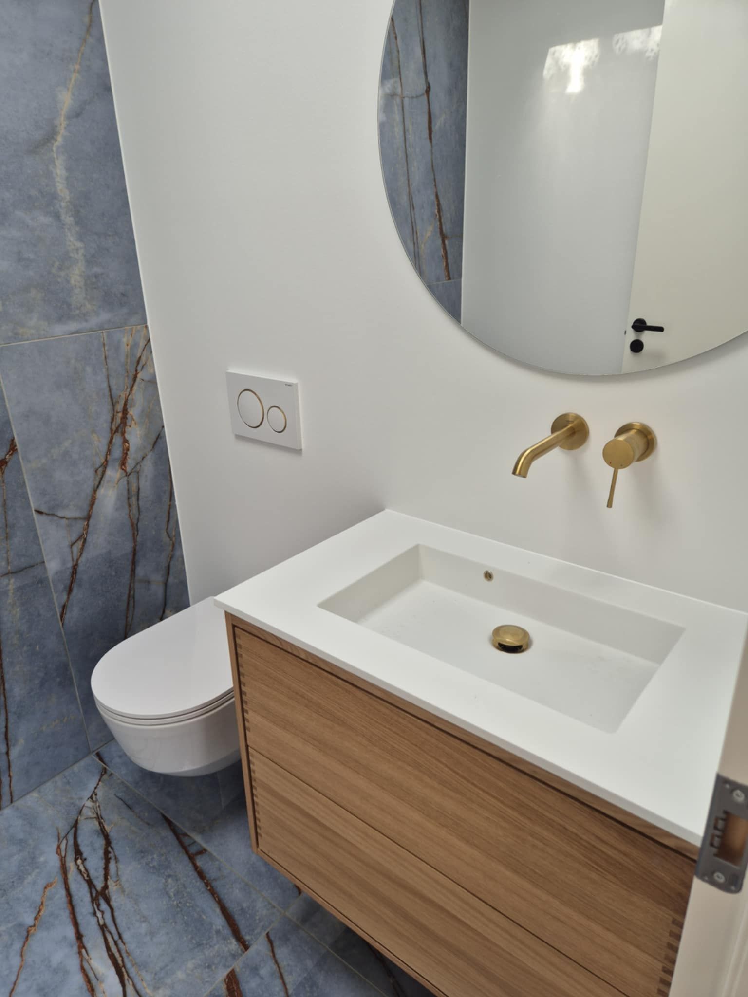 Et badeværelse med håndvask, toilet og spejl.