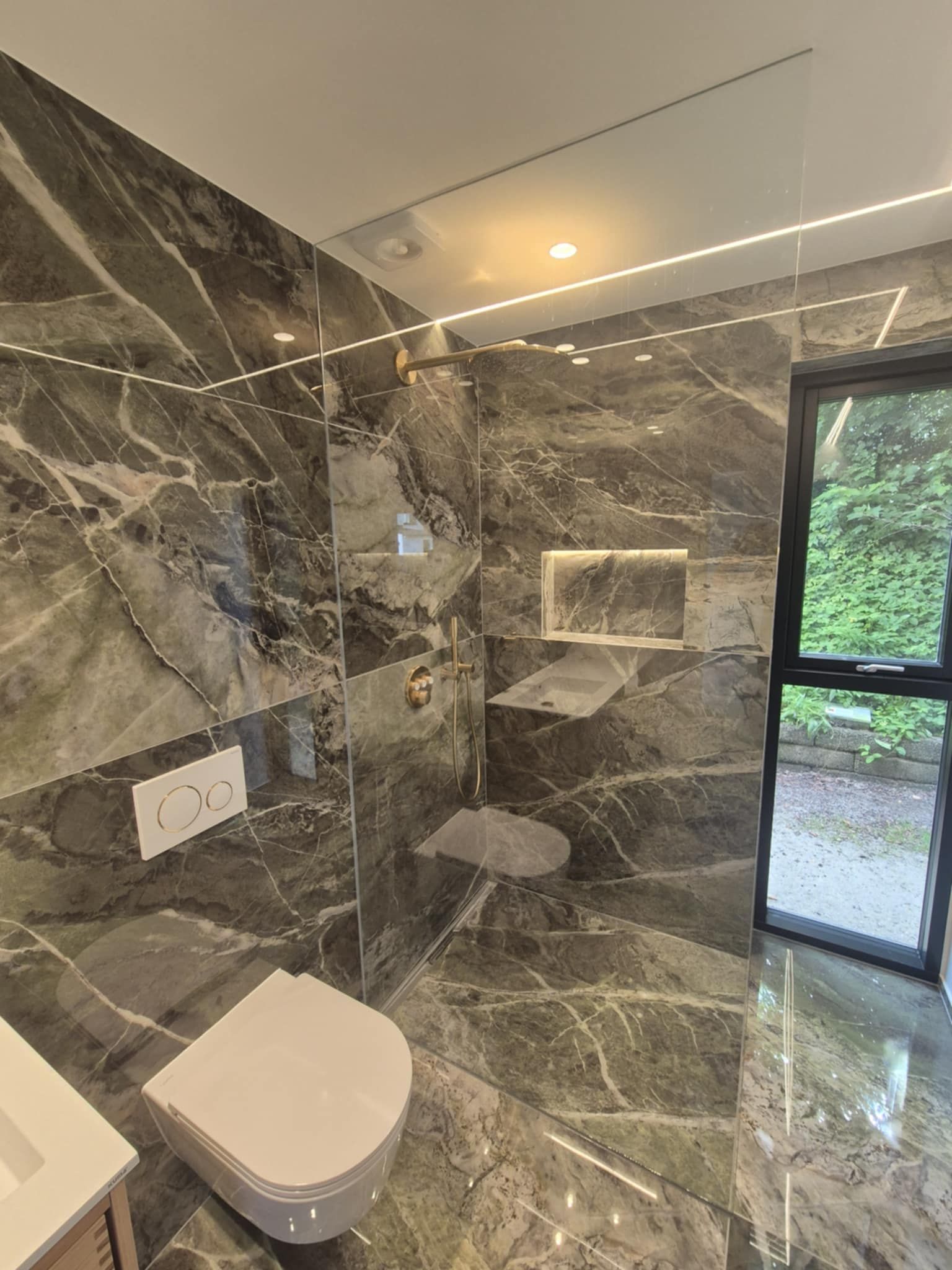 Et badeværelse med toilet, håndvask og bruser.