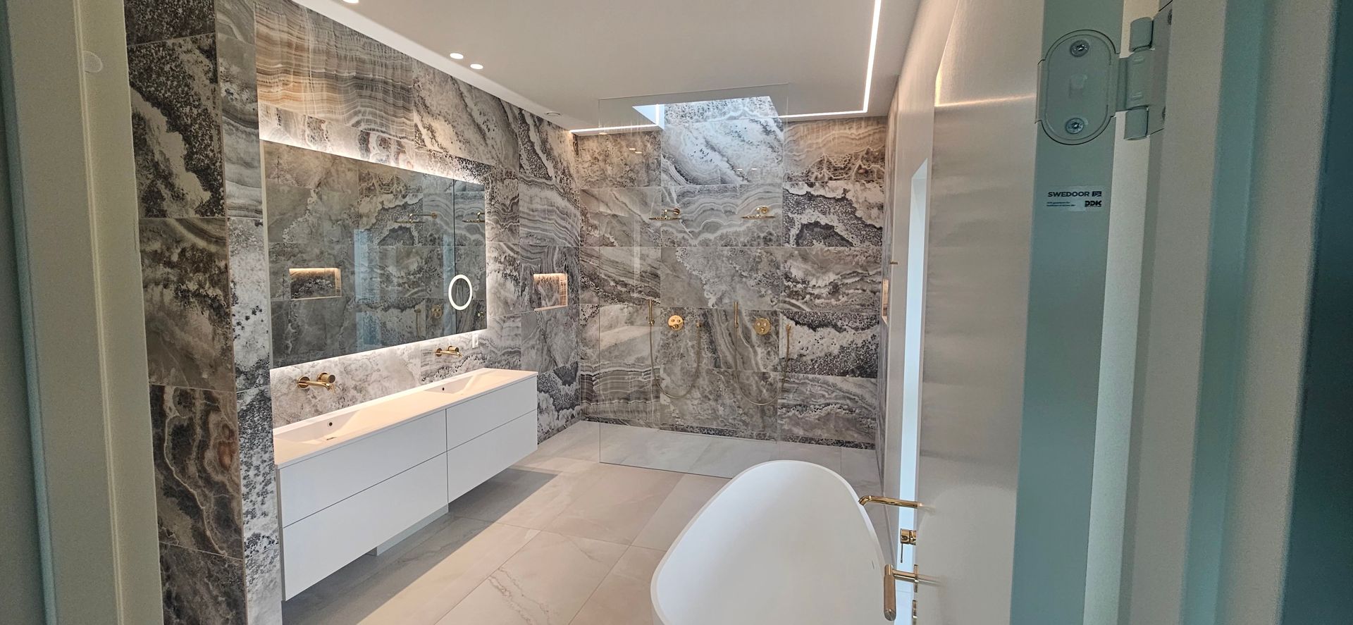 Et badeværelse med to håndvaske, et badekar og en bruser.