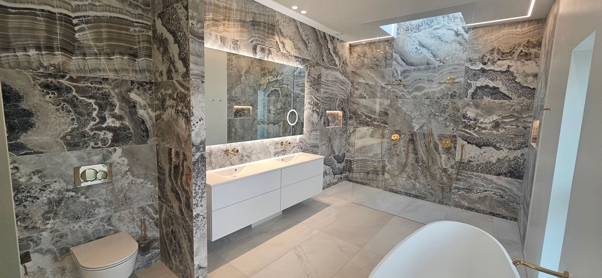 Et badeværelse med badekar, toilet, håndvask og spejl.