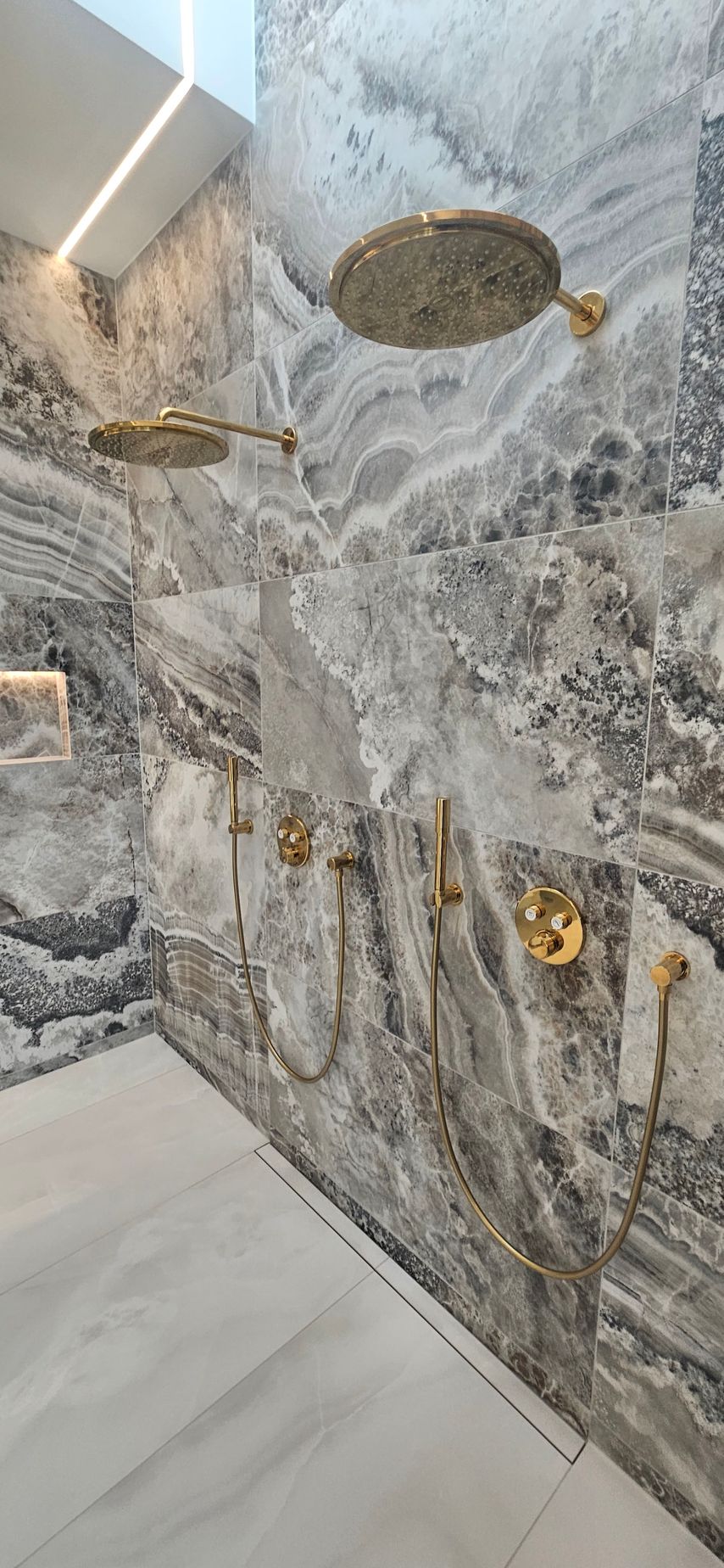 Et badeværelse med mange brusehoveder på væggen.