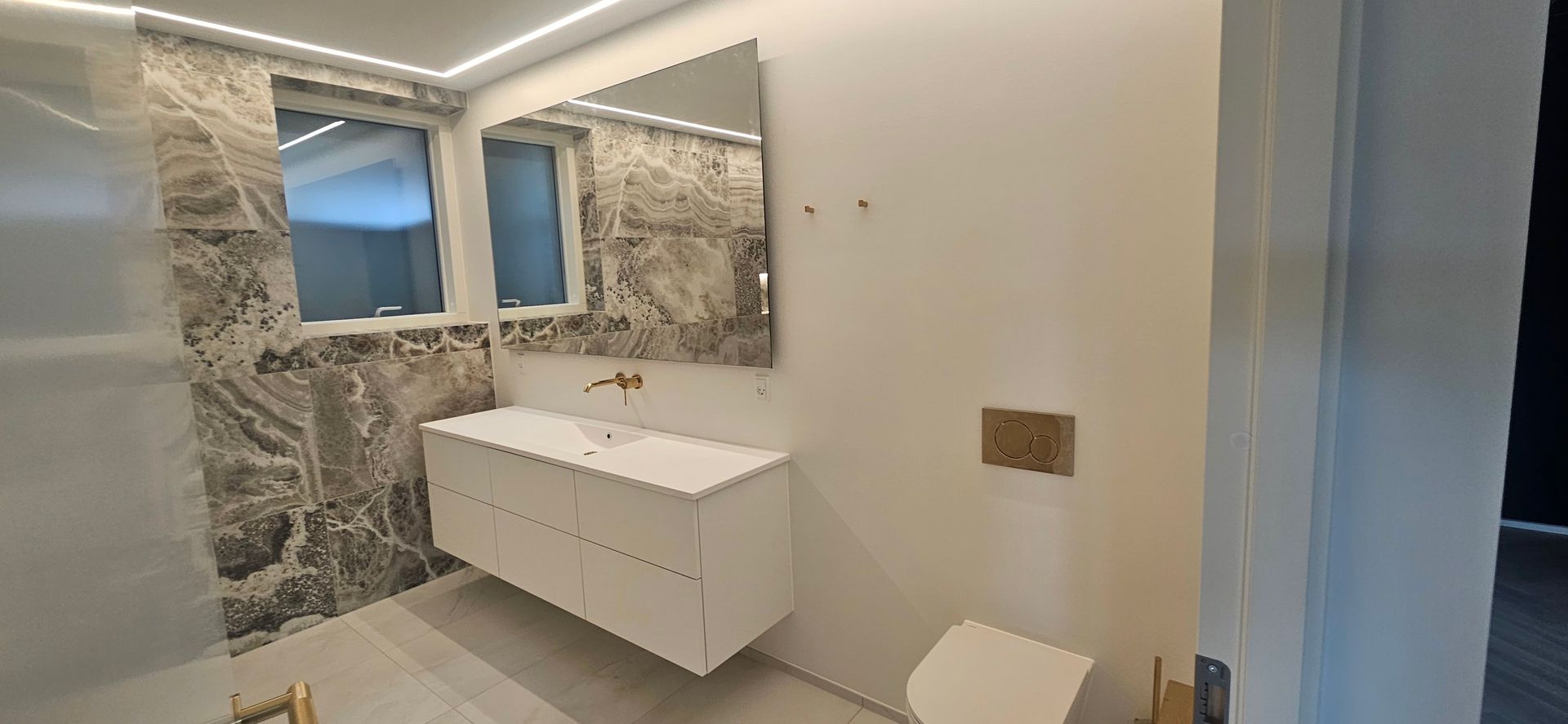 Et badeværelse med håndvask, spejl og toilet.