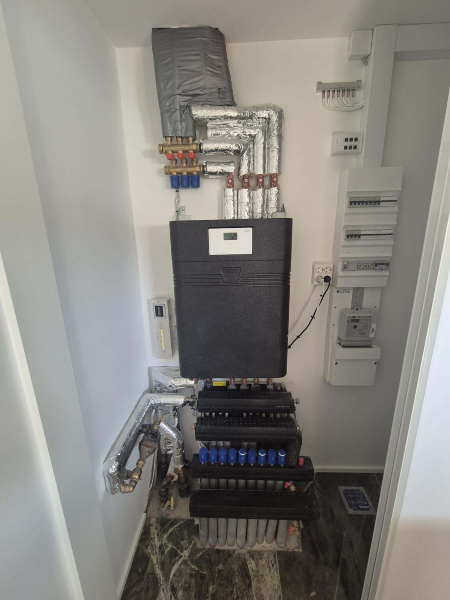 En sort kasse står oven på en hylde i et værelse.