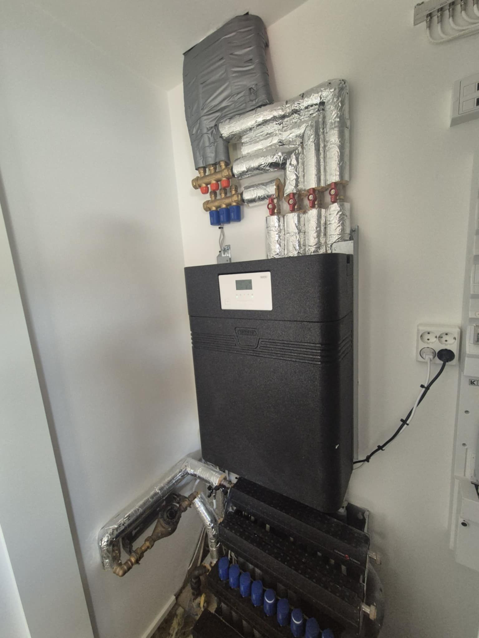 En sort kasse står oven på en stak rør i et rum.