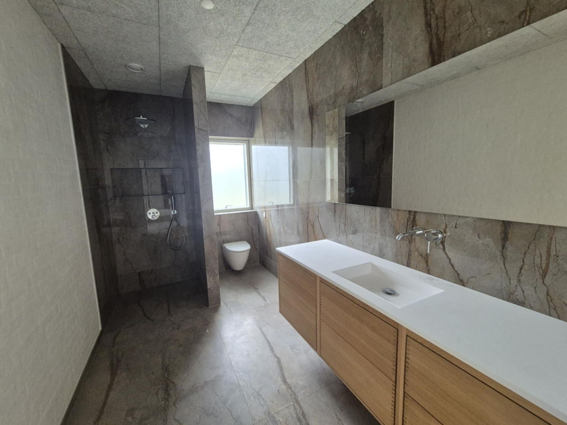 Et badeværelse med toilet, håndvask og spejl