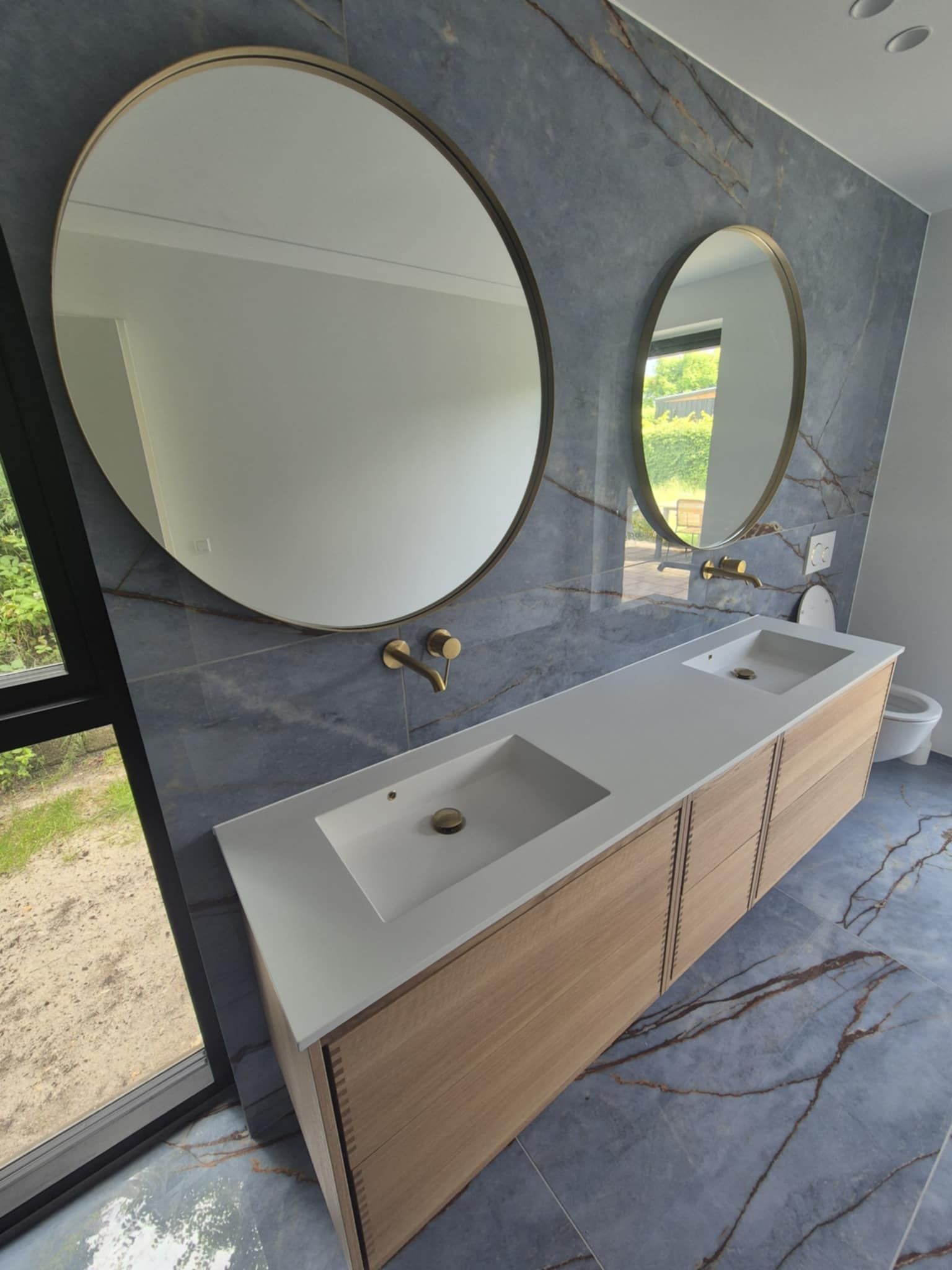 Et badeværelse med to håndvaske og to spejle på væggen.