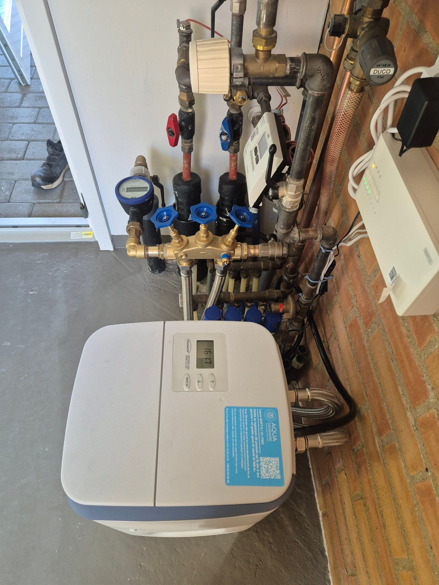 En blødgører sidder ved siden af ​​en flok rør i et rum.