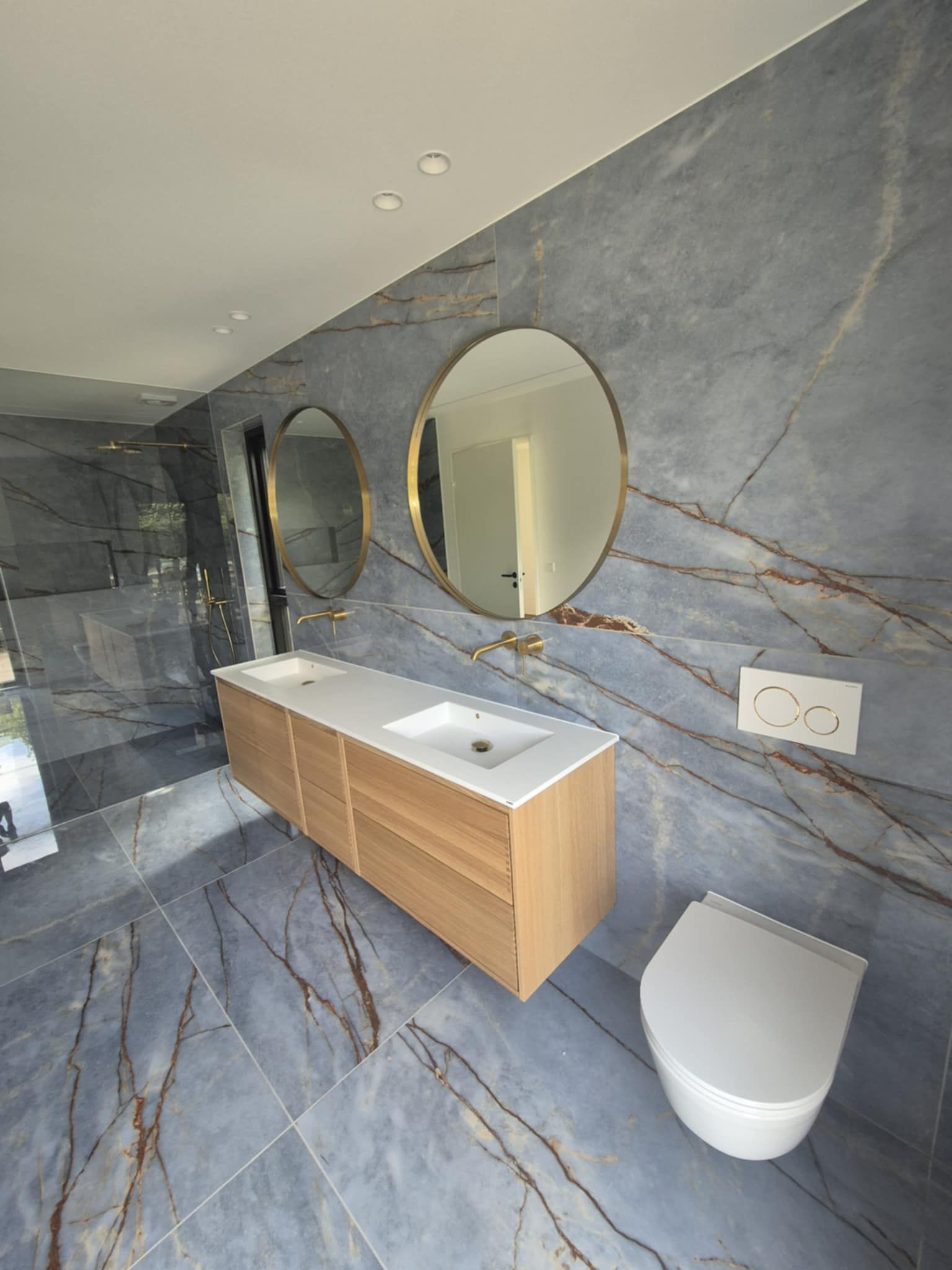 Et badeværelse med håndvask, toilet og to spejle.