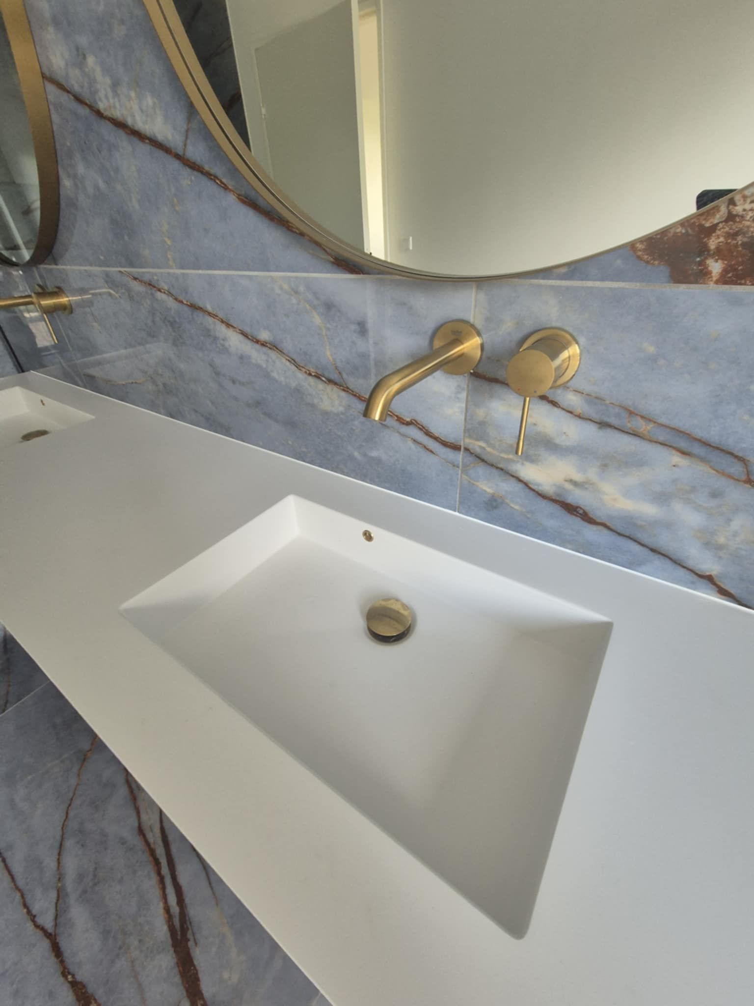 En badeværelsesvask med en gylden vandhane og et spejl