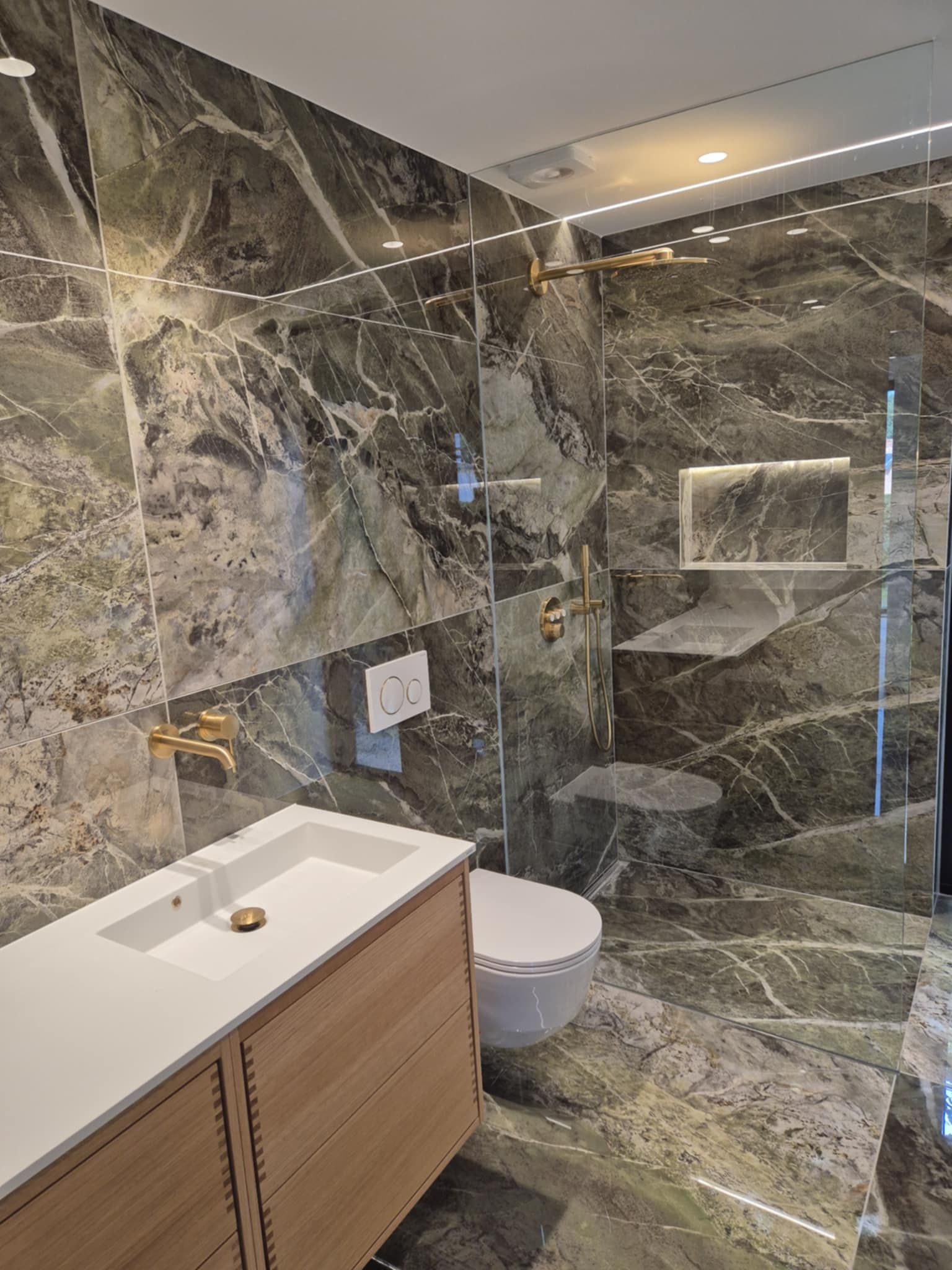 Et badeværelse med håndvask, toilet og bruser.