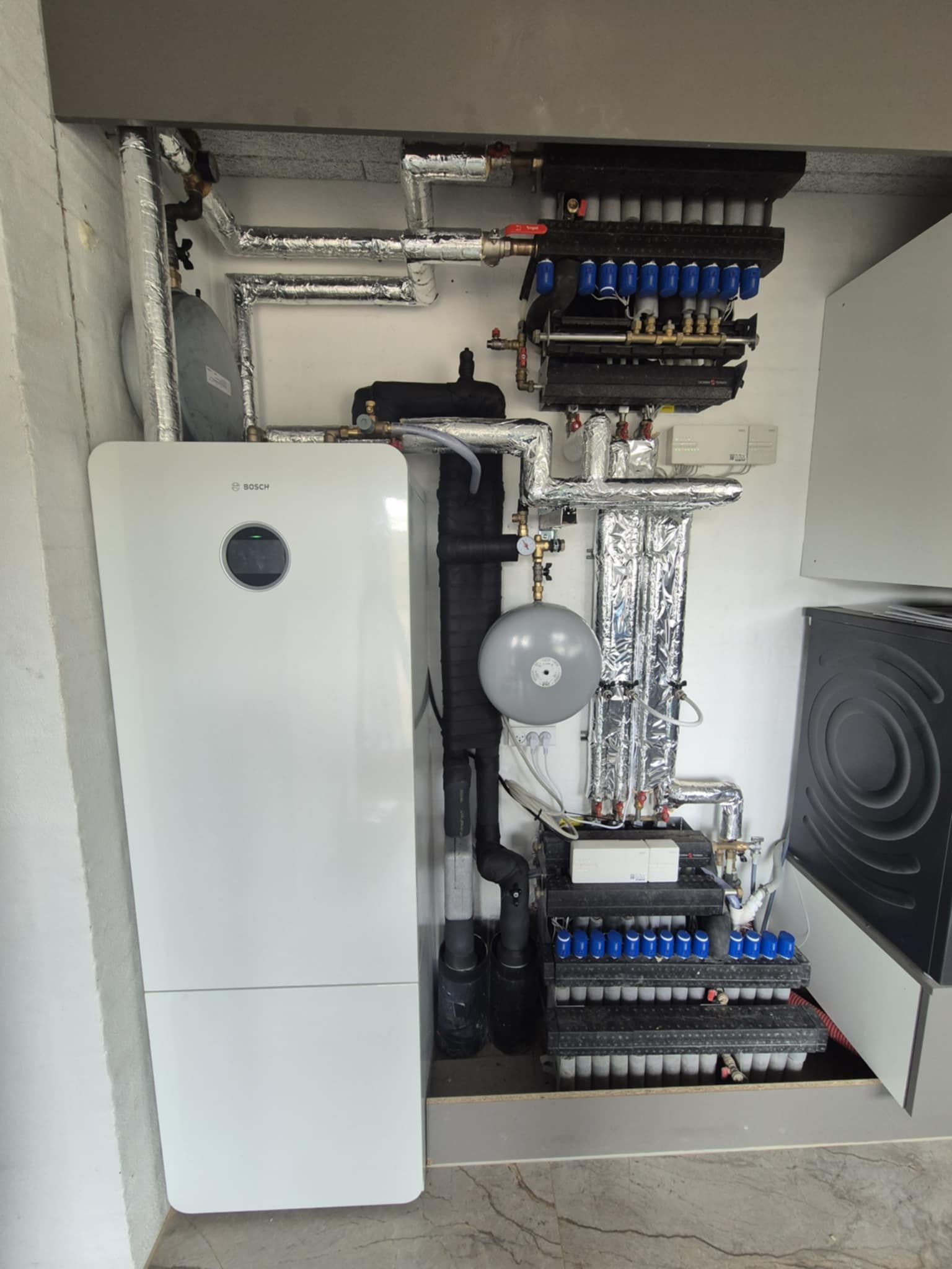 En hvid varmeovn står i et hjørne af et værelse.