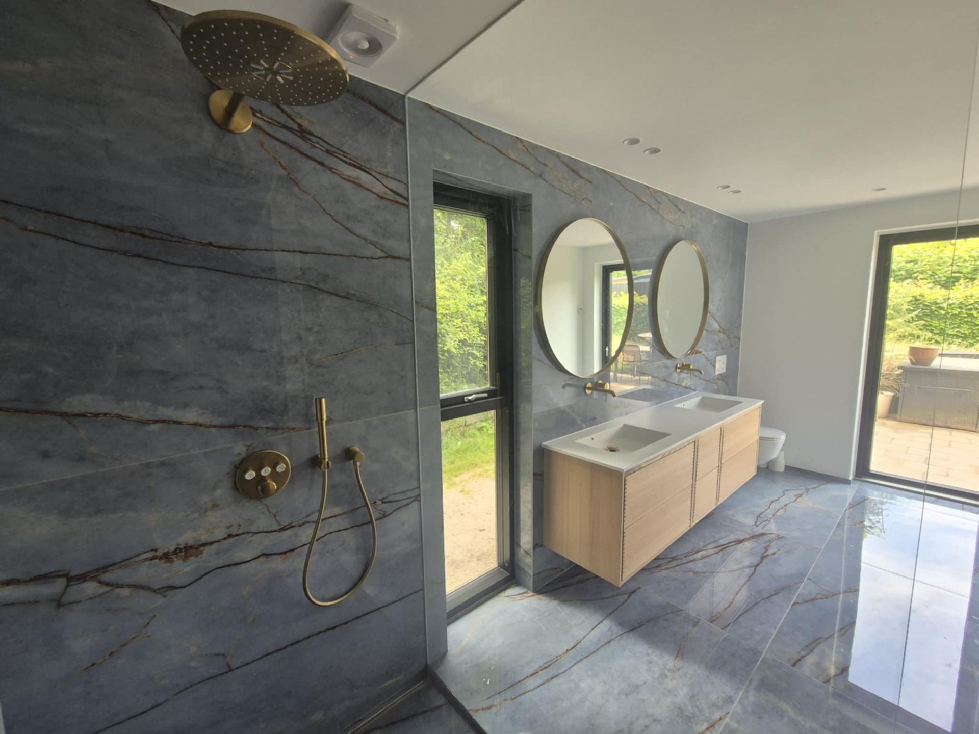 Et badeværelse med bruseniche, håndvask og spejl.