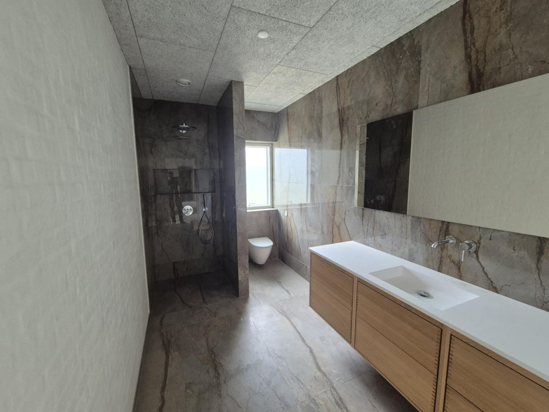 Et badeværelse med toilet, håndvask og spejl