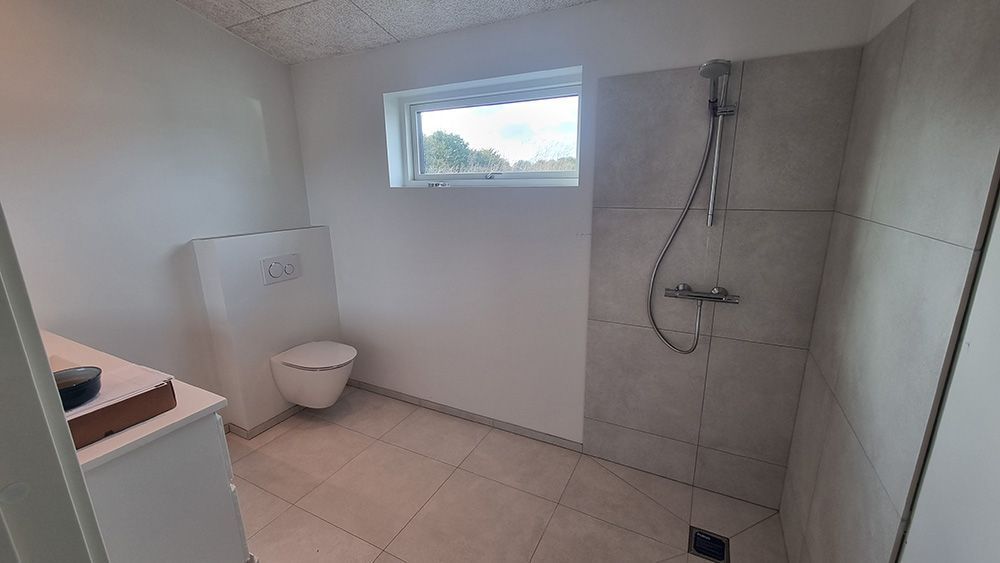 Et badeværelse med toilet og bruser.