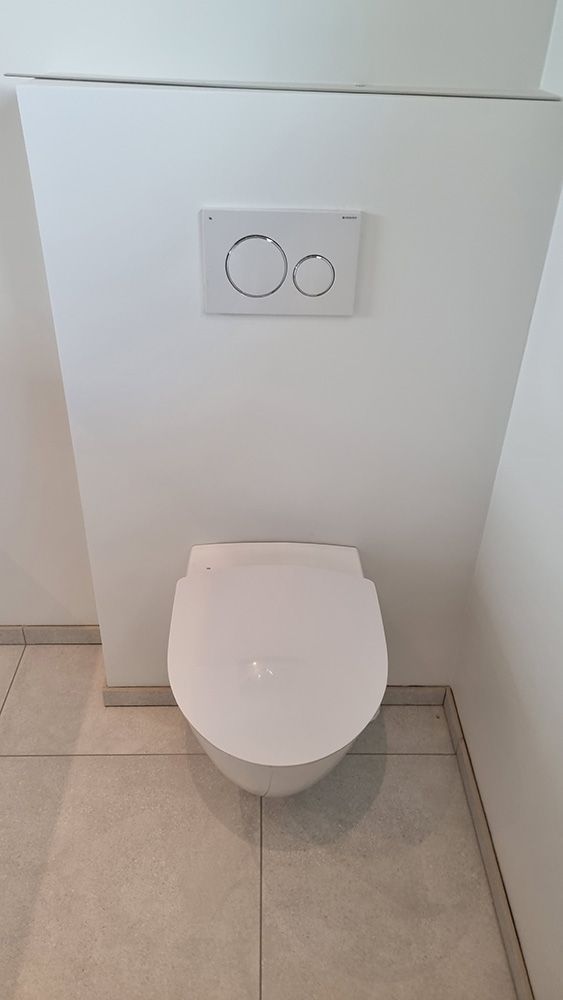 Et hvidt toilet er monteret på en væg i et badeværelse.