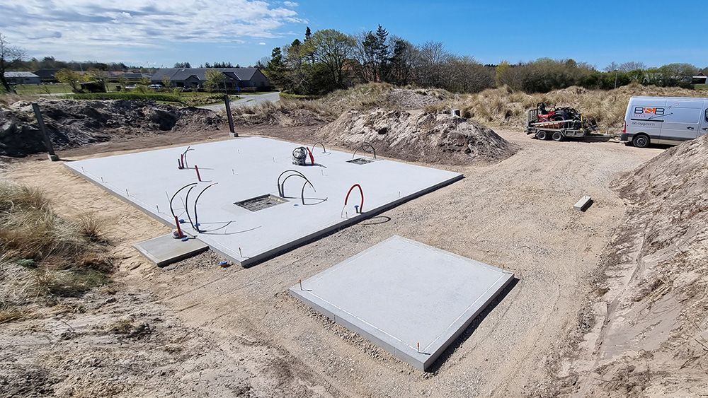 En stor betonplade sidder midt på en jordmark.