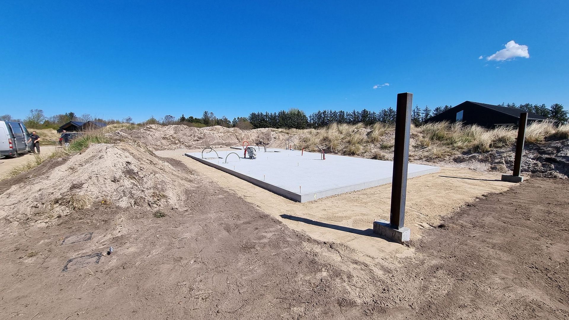 En stor betonplade sidder midt på en jordmark.