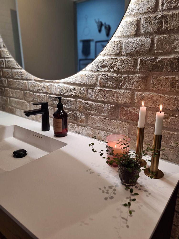 En badeværelsesvask med et spejl og stearinlys på tælleren.
