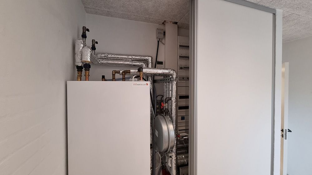 En hvid kasse med rør, der kommer ud af den, står i et skab.