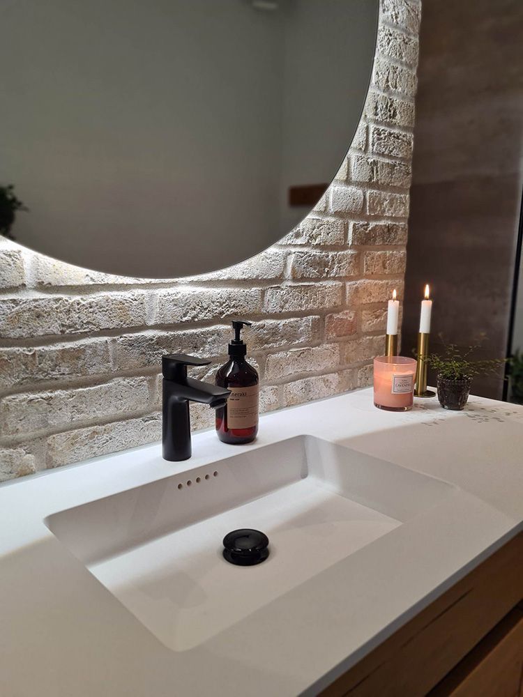 En badeværelsesvask med et spejl og stearinlys på tælleren.