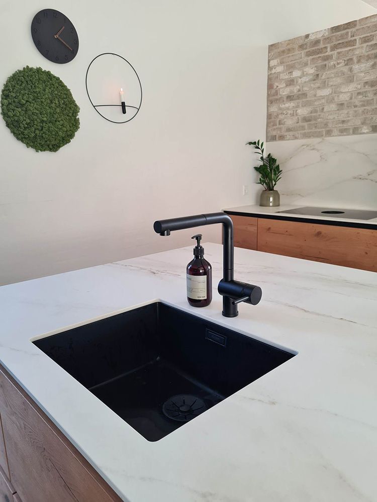 Et køkken med sort vask og sæbedispenser