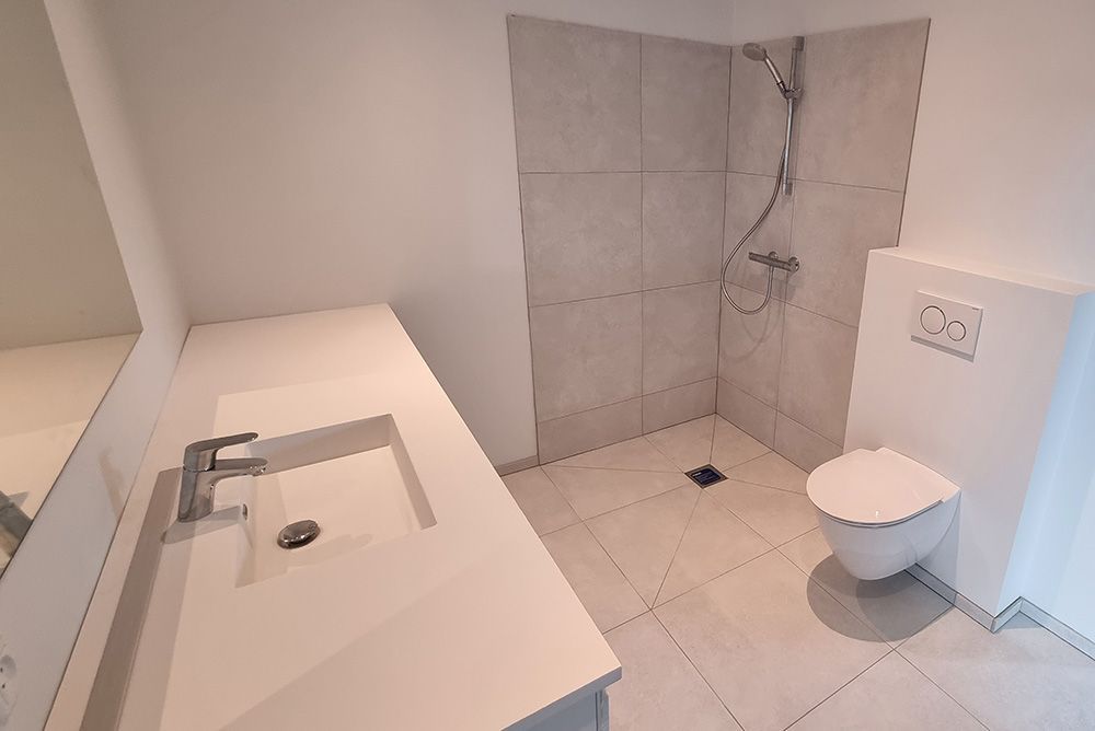 Et badeværelse med håndvask, toilet og bruser.